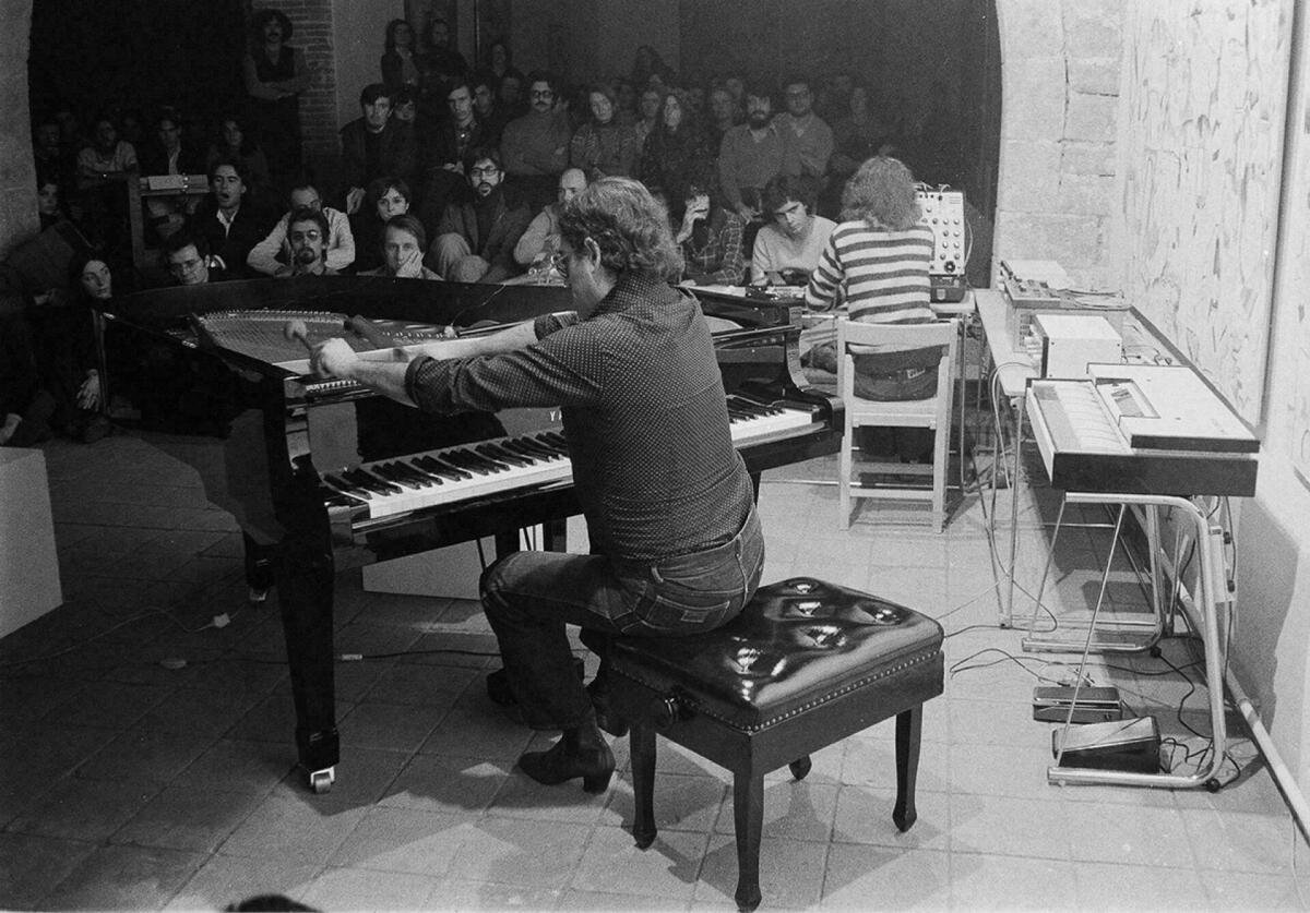 Foto en blanc i negre. Es veu el músic Carles Santos davant del piano actuant