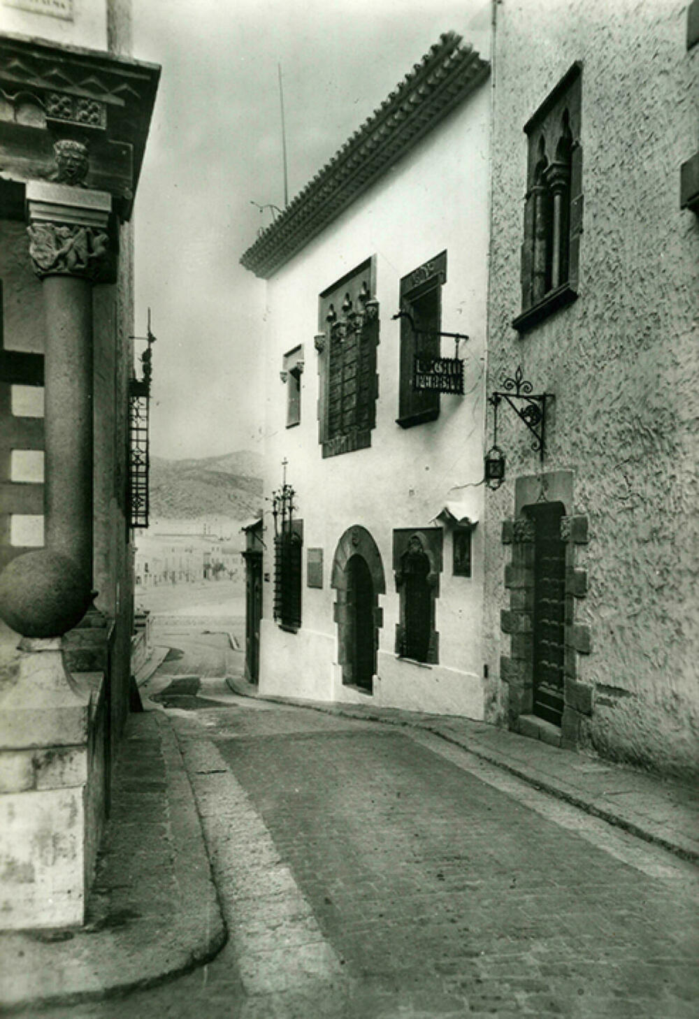 Postal en blanc i negre. Es veu el carrer i la façana del Museu Cau Ferrat de Sitges