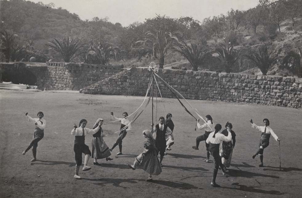 Foto en blanc i negre de joves en rotllana fent el "Ball de Gitanes" al Parc Güell, una dansa popular