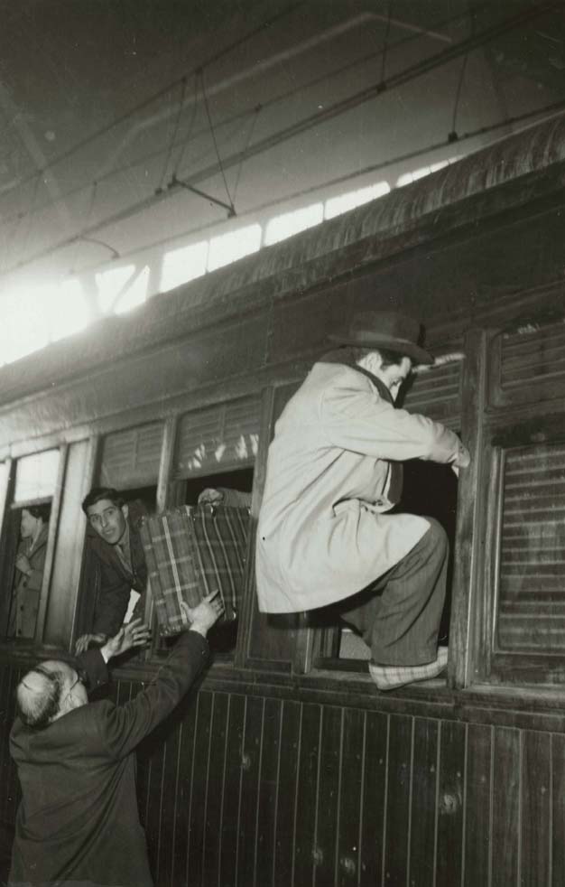Foto en blanc i negre d'home entrant al tren per la finestra del tren a L'estació de França