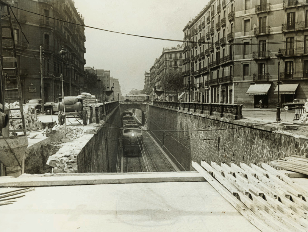 El carrer Aragó, amb un tren circulant, durant les obres de cobertura de les vies. 4 de novembre 1957. AFB. Autor: desconegut