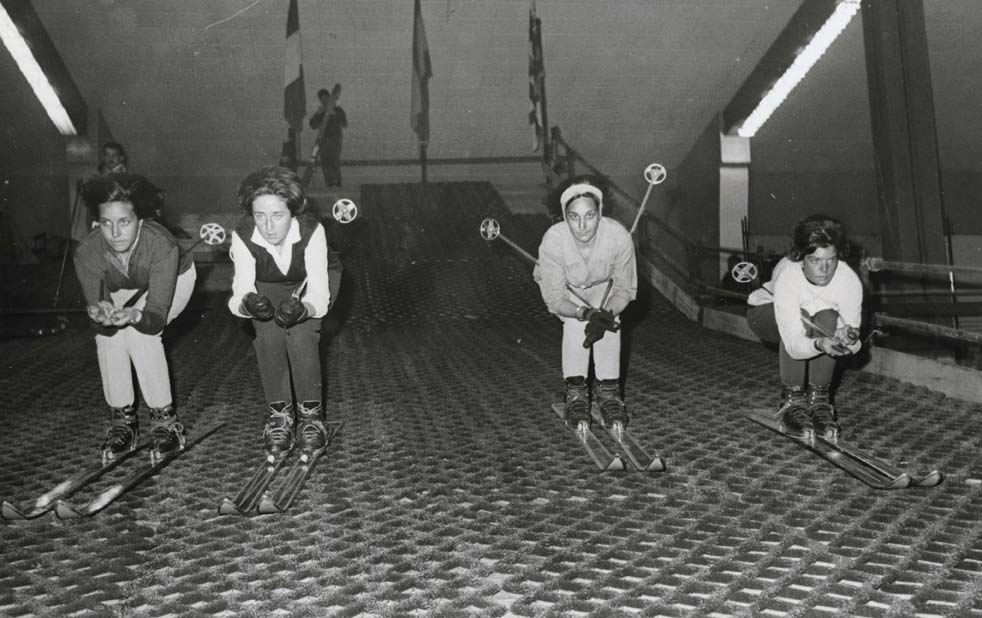 Foto en blanc i negre de quatre joves esquiant sense neu al Saló de Turisme i esport a Montjuïc