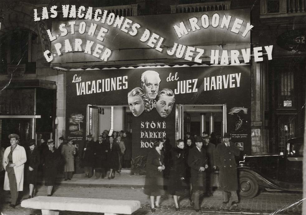 Fotografia en blanc i negre de la sortida del cinema "Fémina", on es pot veure el cartell de la pel·lícula "Les vacances de Jutge Harvey"