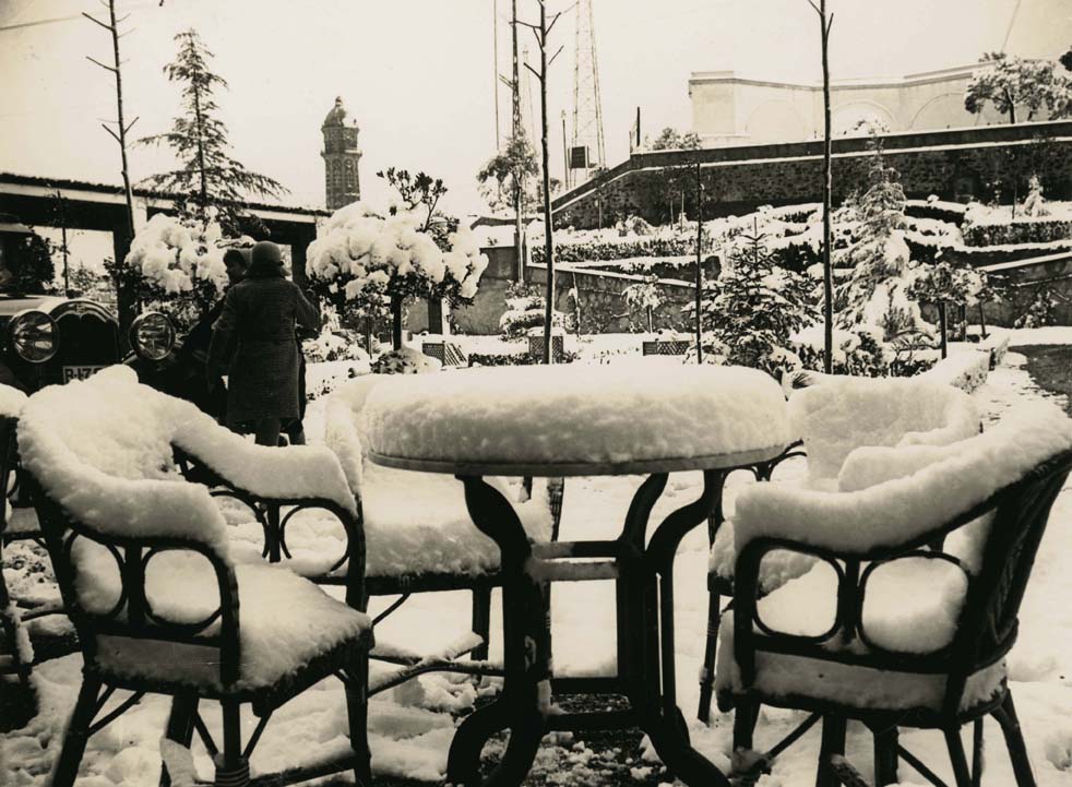 Foto en blanc i negre. Es veuen dues cadires i una taula de la terrassa de bar del Tibidabo amb 15 centímetres de neu al damunt