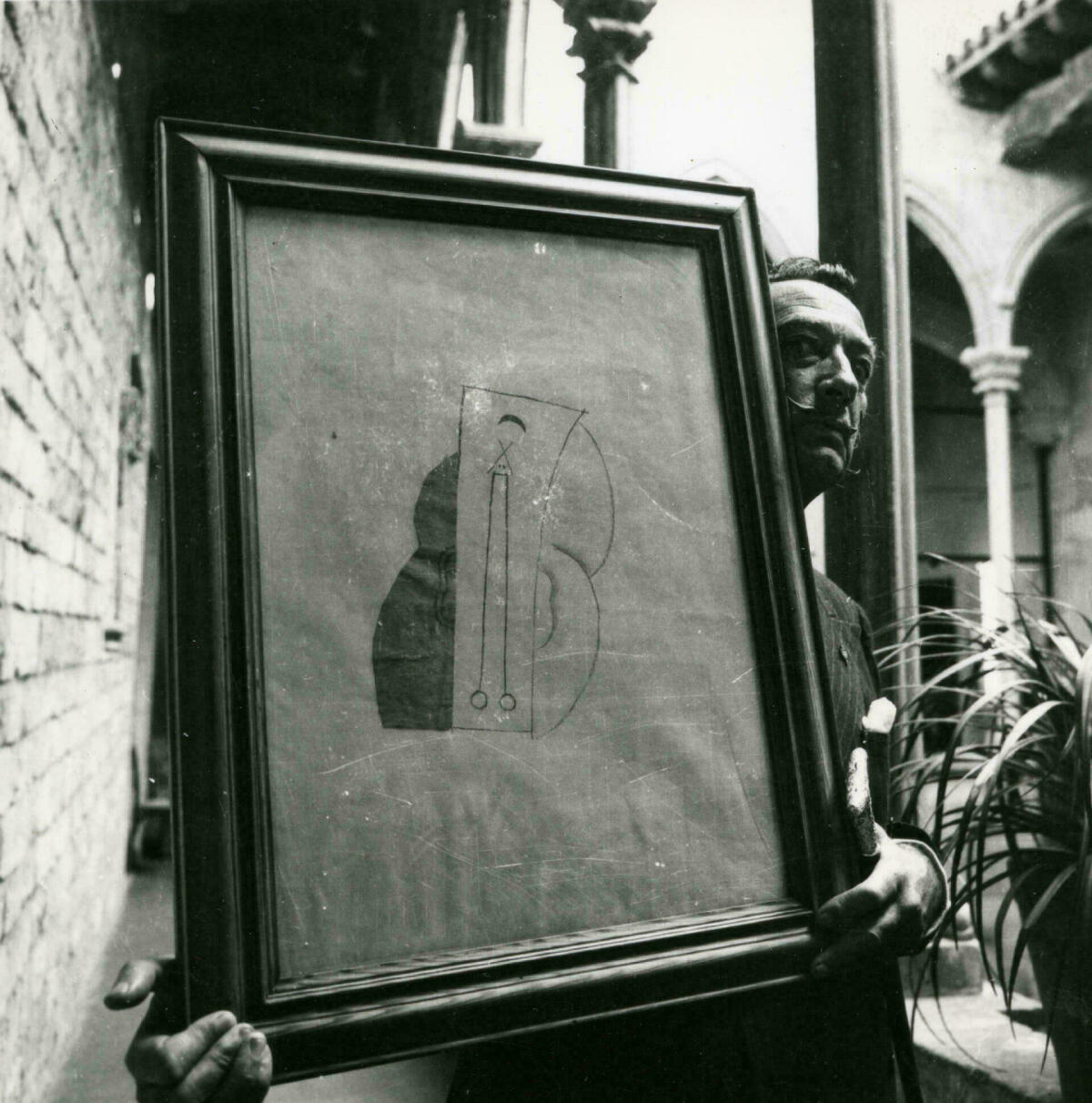 Salvador Dalí, al Museu Picasso, amb l'obra cubista 'Cap' de Pablo Picasso que Gala i ell donaren a aquesta institució, 1963. AFB. Josep Postius
