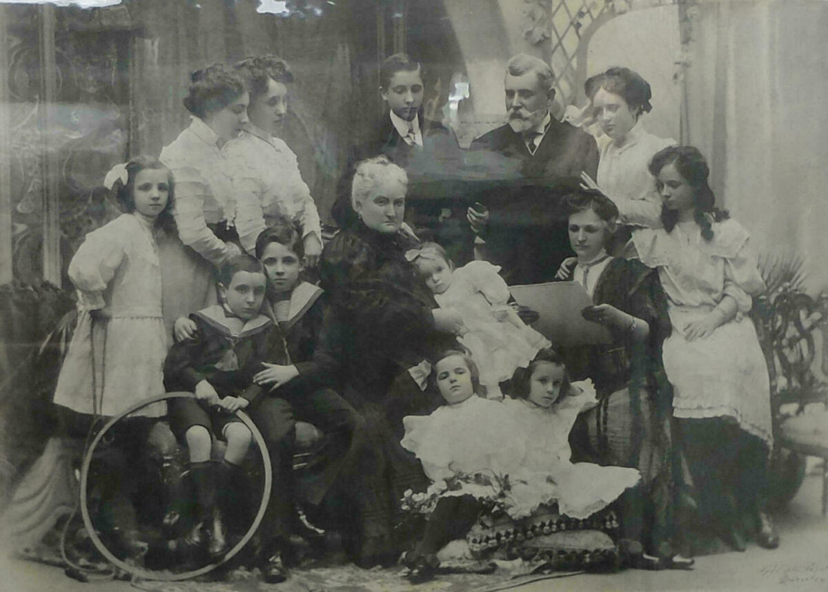 Retrat en blan i negre de la família tomàs Farell. Es veu un matrimoni envoltat dels seus 12 fills, vestits amb elegància 