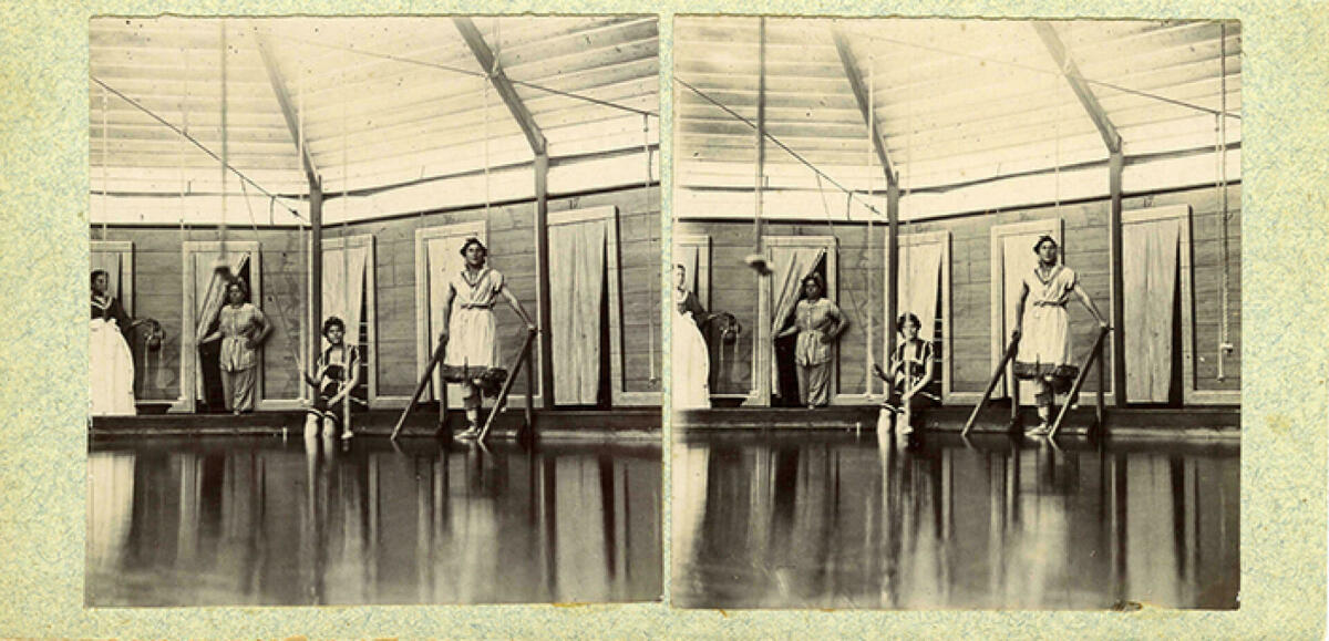 Foto en blanc i negre. Es veu una piscina pública reservada a dones que porten banyadors antics que tapen el cos