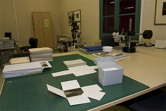 Foto a color. Es veu el laboratori de conservació amb material fotogràfic de conservació damunt una taula de treball
