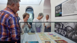 Several people looking at a glass case showing the programmes for the Sants festa major