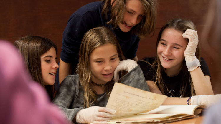 A group of children looking at a document and smiling.