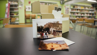 Un seguit de fotografíes en color, col·locades sobre una taula de la sala de consulta d’un arxiu