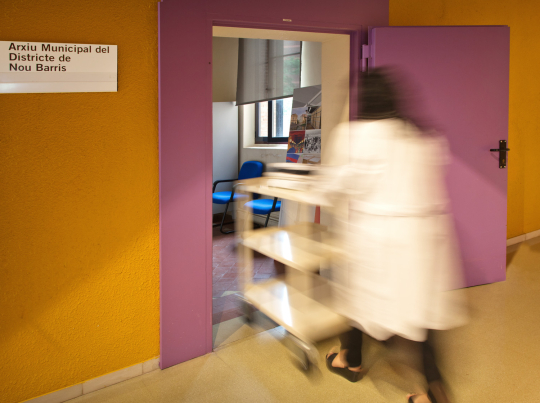A person with a cart carrying documents enters the reference room of the AMDNB through the entrance door
