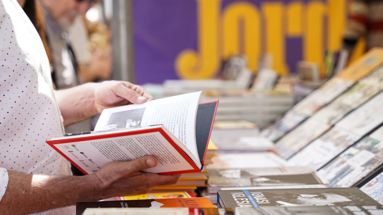 Persona fullejant llibre a la parada de Barcelona Llibres de Sant Jordi