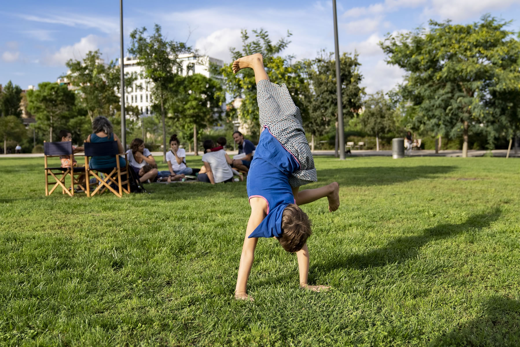 Girl doing a somersault on the grass in a park surrounded by vegetation