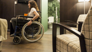 Dona amb cadira de rodes amb una habitació d'hotel adaptada