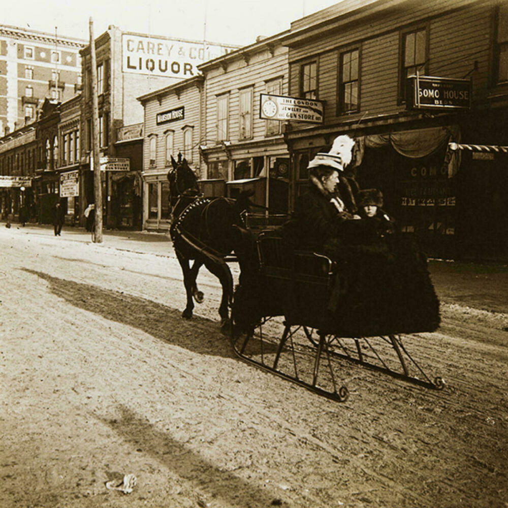 Es veu trineu ocupat per una senyora i arrossegat per un cavall, per un carrer de Winnipeg. Canadà