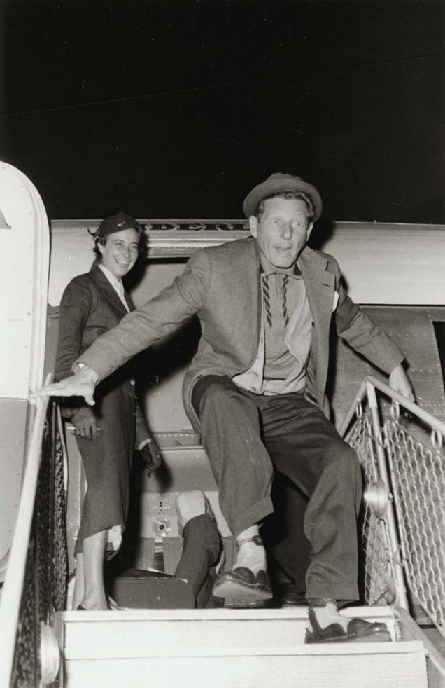 Foto en blanc i negre, retrat de Danny Kaye baixant les escales de l'avió a l' arribada a l'aeroport del Prat