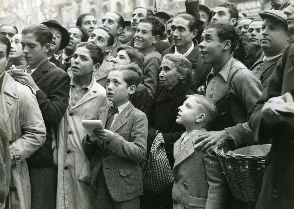 La rifa de Nadal. Primer pla d'un grup de gent esperant els resultats de la grossa. 21 de desembre de 1935. AFB. Carlos Pérez de Rozas