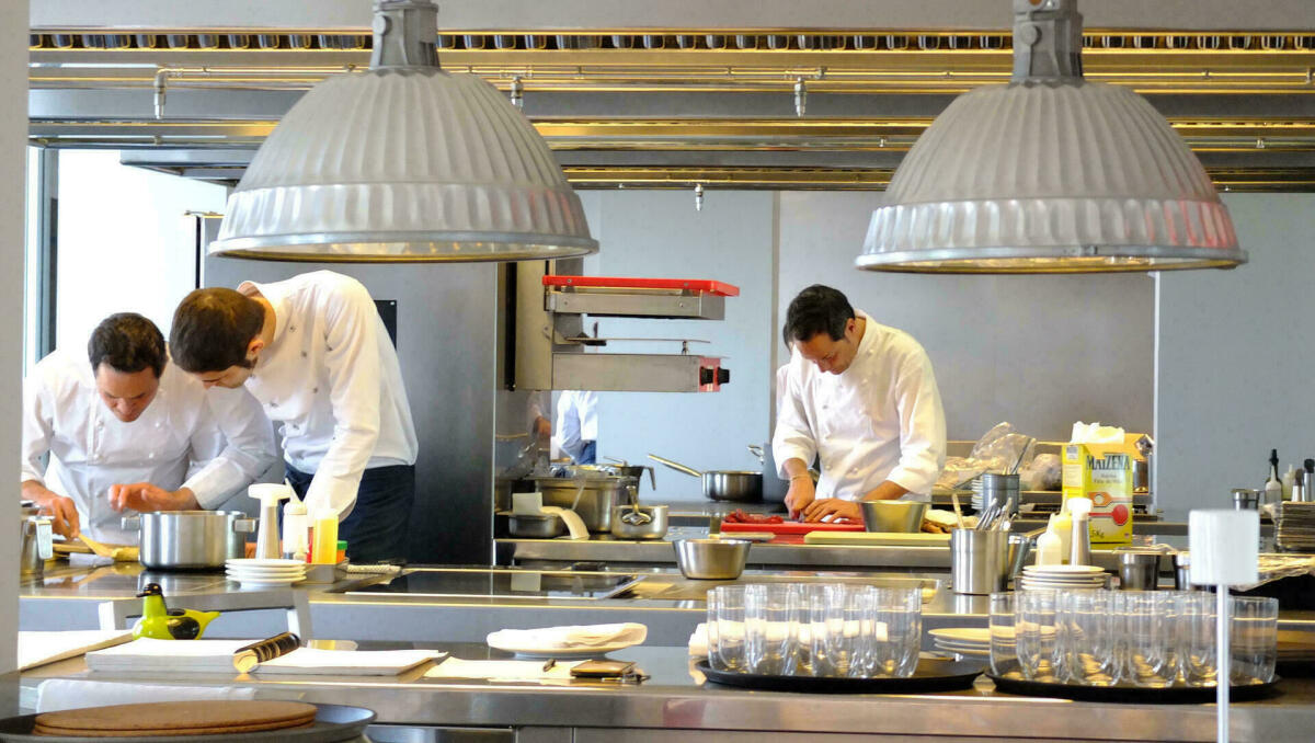 Fotografia color de l'interior de la cuina dels restaurant Dos Cielos on hi ha tres cuiners treballant