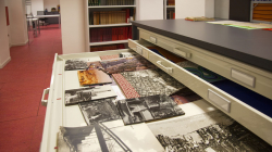 An archive cabinet with an open drawer containing several photographs, of various sizes, in black and white and in colour