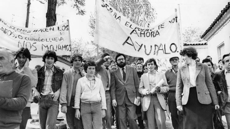 Mayor Narcís Serra visiting Can Peguera, accompanied by a group of local residents with placards, 1981