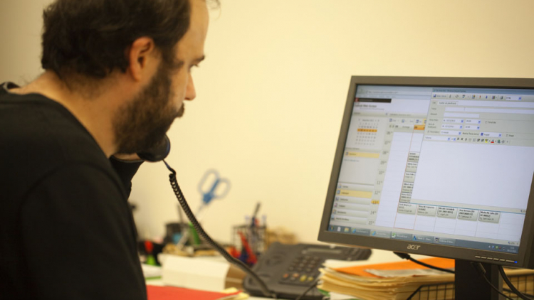 Una persona parla per telèfon al mateix temps que contempla una pantalla d'ordinador on apareix un formulari de correu electrònic