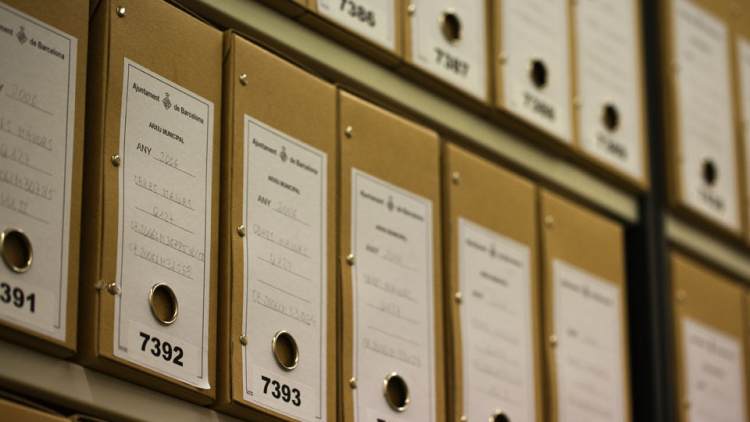 A series of boxes of records on a shelf in a storage room at the AMDHG.