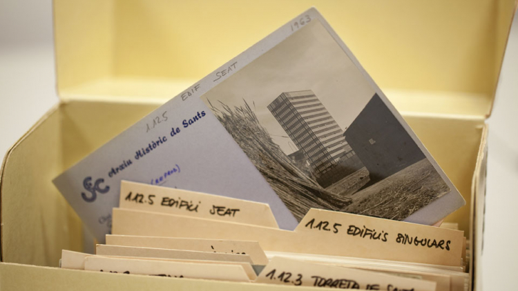 Una caixa-fitxer oberta i d’entre les fitxes en sobresurt una amb una fotografia en blanc i negre de l’edifici Seat del 1963