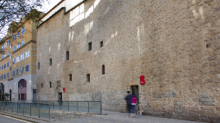 Imagen de la fachada de piedra de un edificio de tres plantas, con oberturas de pequeñas dimensioneos en dos plantas, que ocupa el AMDCV