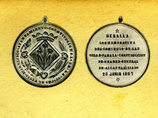 Imatge doble de l'anvers i revers d'una medalla de l'Ajuntament de Gràcia commemorativa de l'inici de les obres de la xarxa de clavegueram de Gràcia, 26 de juny de 1887.