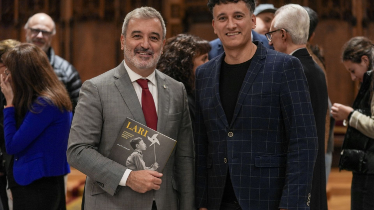 L'Alcalde Jaume Collboni sostenint el llibre Lari amb el Mag Lari al costat.