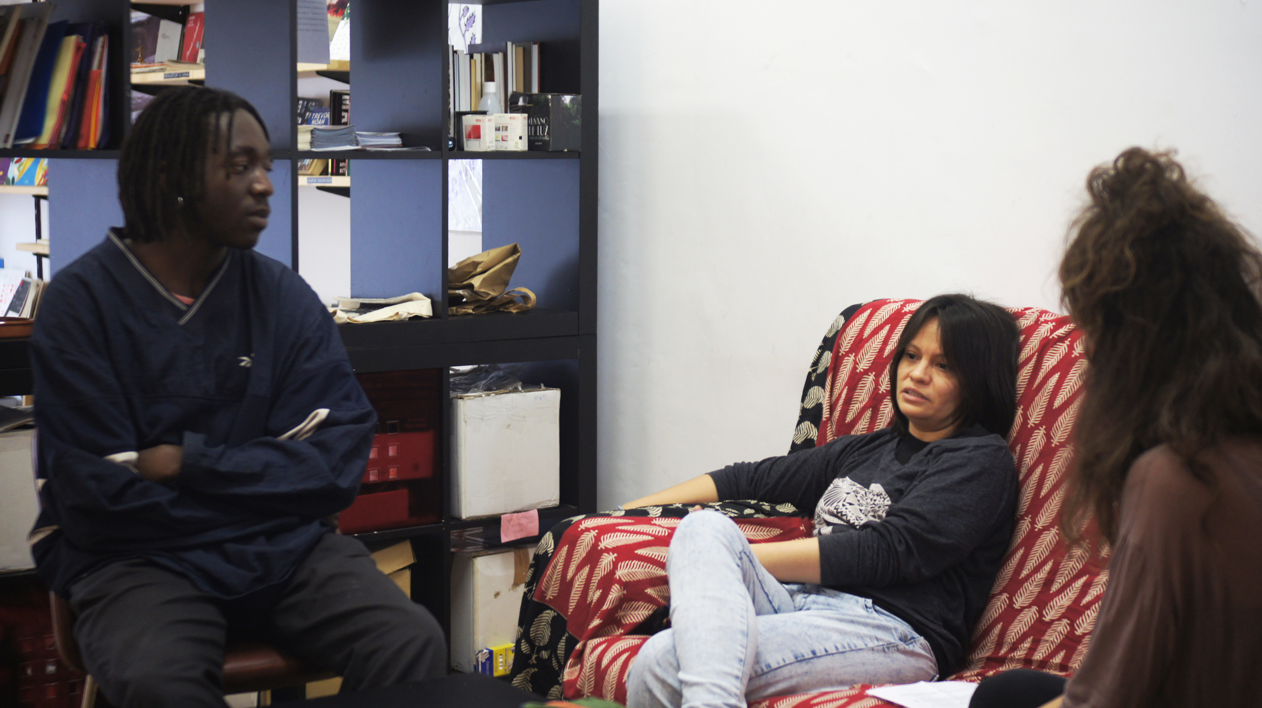 Una noia (Guadalupe) asseguda a un sofà i un noi (George) assegut a una cadira, mentre una altra noia els fa una entrevista. (© Violeta Ospina)