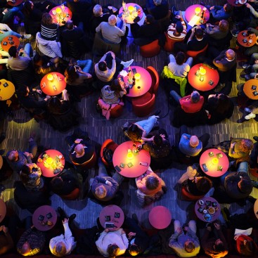 Bar de nit, moltes taules amb petites llums al centre, gent al voltant de les taules