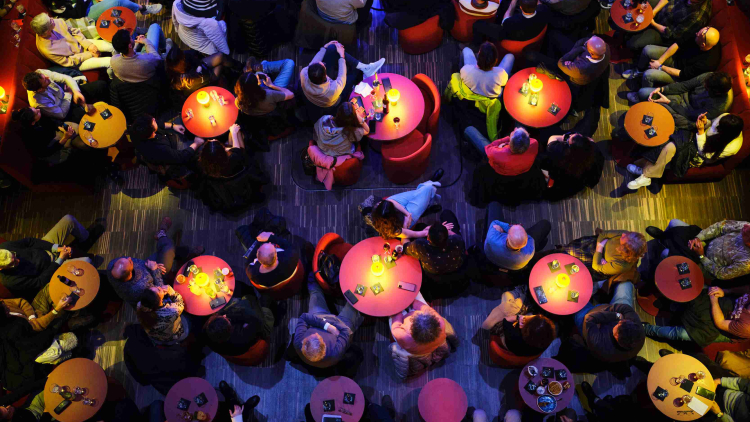 Bar de nit, moltes taules amb petites llums al centre, gent al voltant de les taules