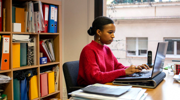  mujer trabajando en una oficina y tecleando en un ordenador portátil