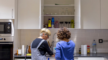 dos mujeres de espaldas hacen trabajo doméstico limpiando los platos en una cocina