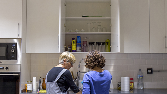 dues dones d'esquenes fan treball domèstic netejant els plats en una cuina