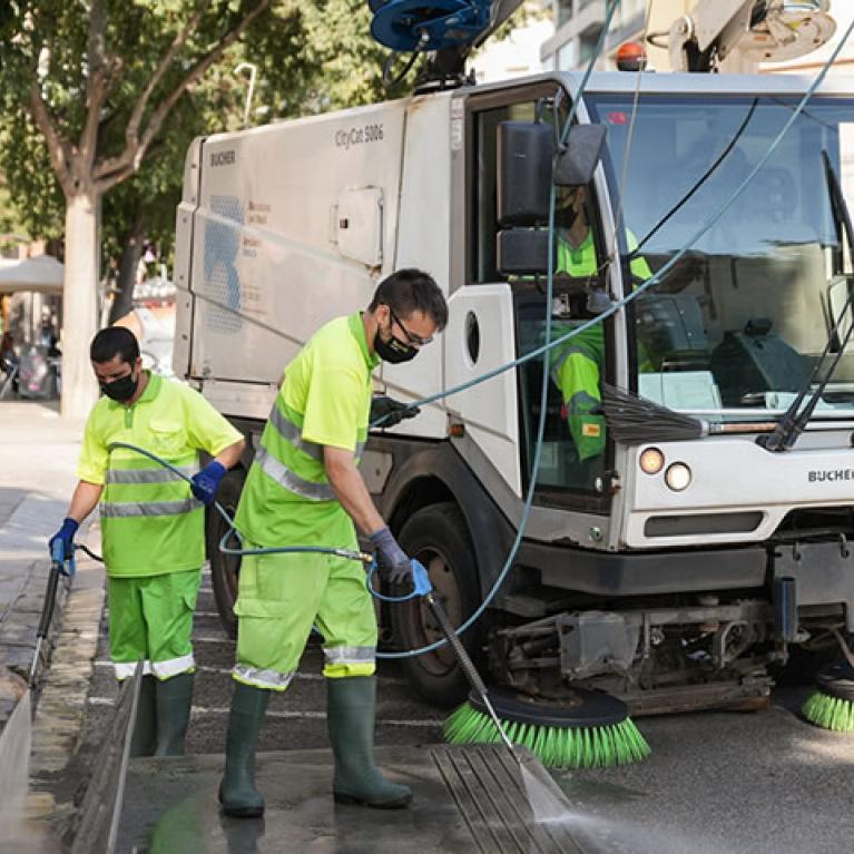 Operaris netejant carrer amb mangueres