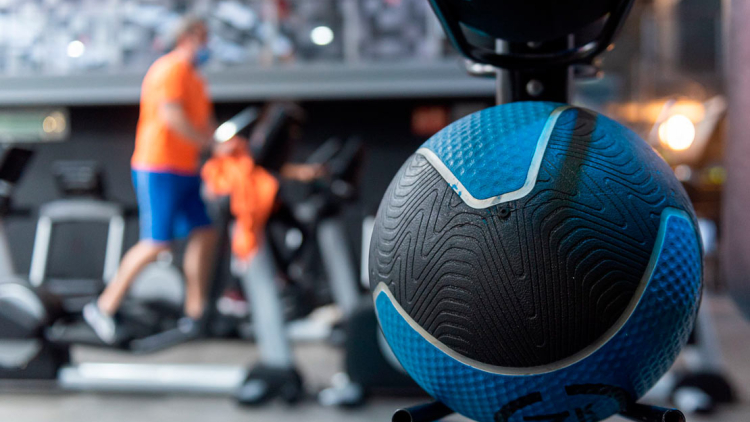 Detall d'una pilota en primer terme, al fons una persona corrent a la cinta