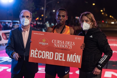 Corredor sostenint un cartell on s'indica que ha batut el Rècord del món, a la Cursa dels Nassos