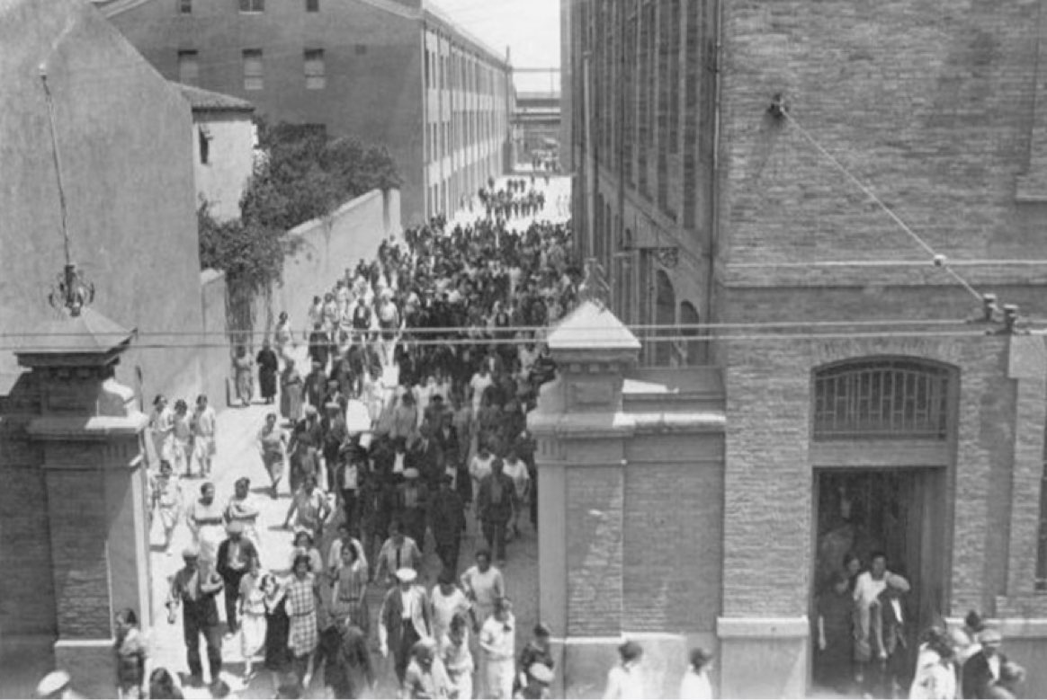 Imatge històrica en blanc i negre de la sortida dels obrers de la fàbrica