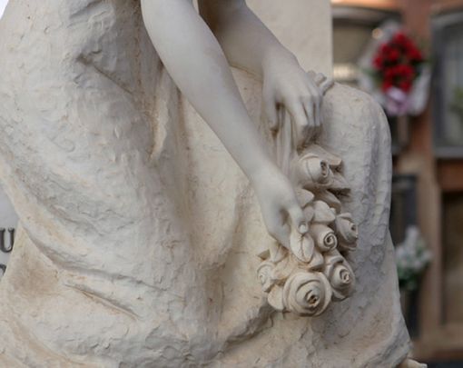 Detall de l'escultura dona asseguda, les mans amb flors