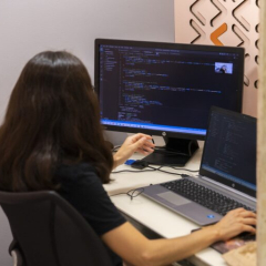 Una dona treballant amb dues pantalles d'ordinador.
