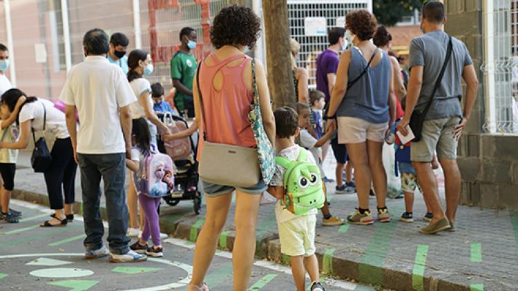 Pares, mares i infants esperant a la porta d'una escola